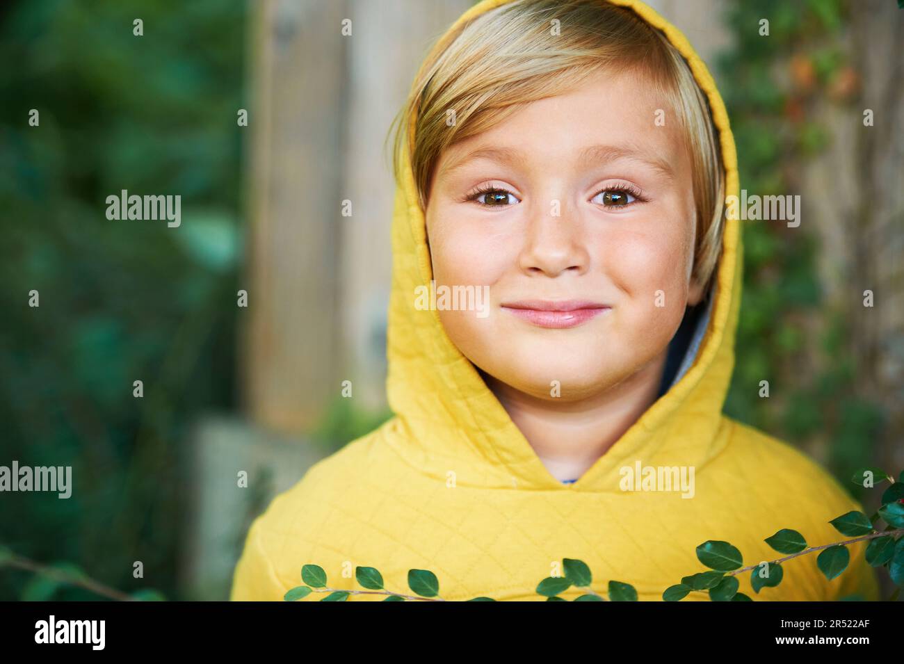 Outdoor portrait of adorable 5 year old boy wearing yellow hoodie Stock