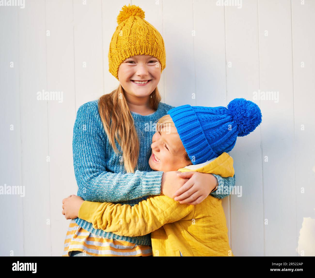 Outdoor portrait of 2 funny kids wearing yellow and blue clothes