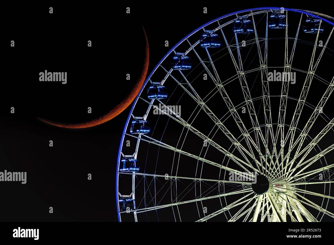 Crescent Moon - The Crescent Moon sets and it is seen by the illuminated Dream Wheel ferris wheel at American Dream mall in Rutherford, New Jersey. Stock Photo