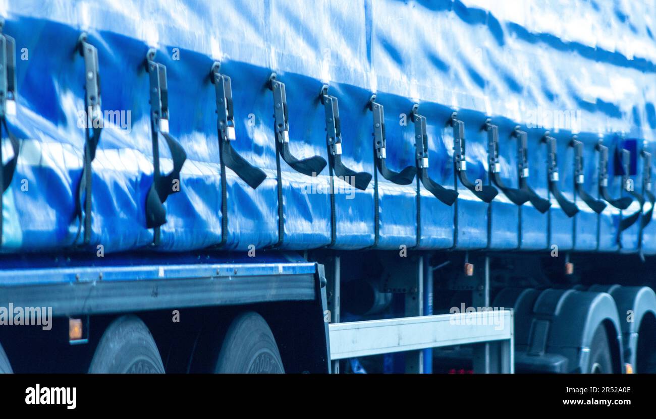 Straps on the side of an articulated lorry flap around in the wind, whilst traveling along a motorway in the UK. Stock Photo