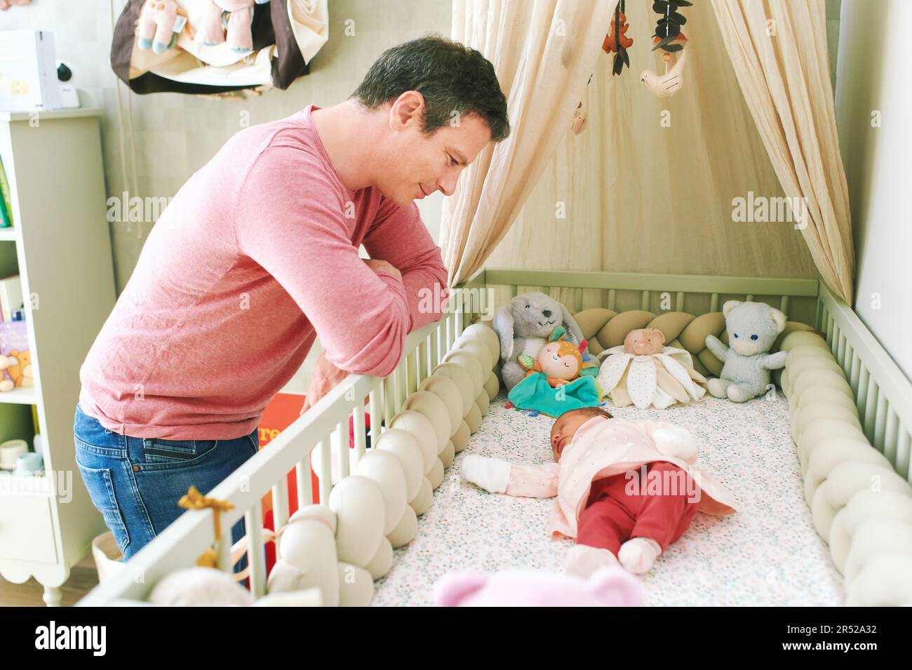 Father admiring how newborn baby sleeping in crib, first days of life