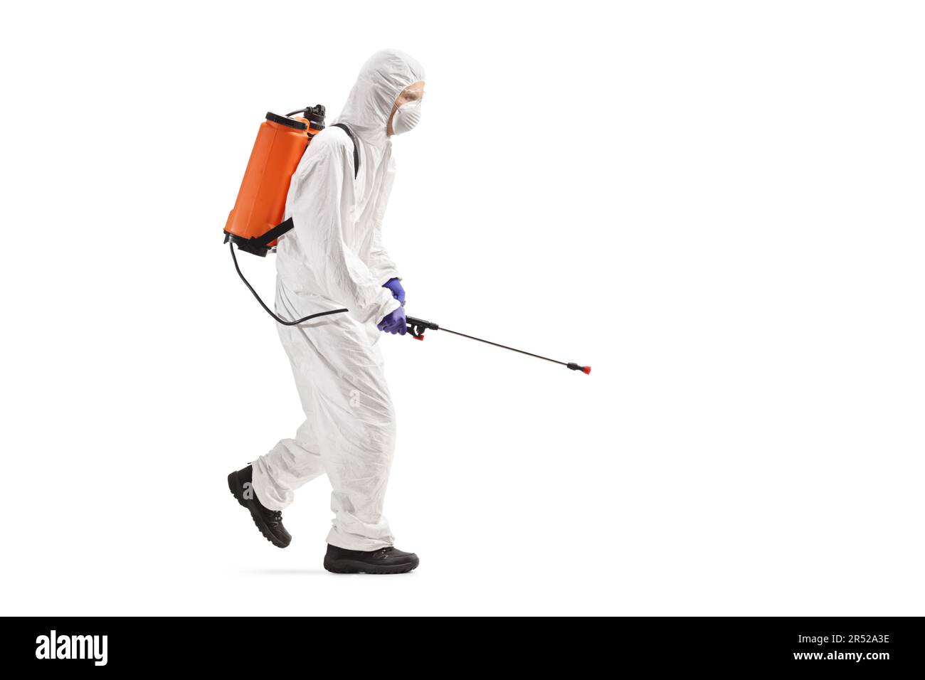 Full length profile shot of a professional worker in a hazmat suit walking and spraying a disinfectant isolated on white background Stock Photo