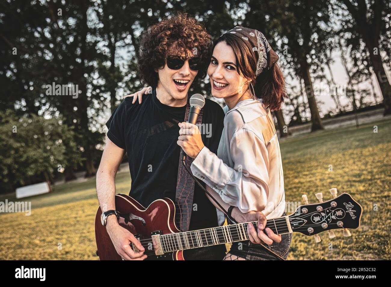 Outdoor park portrait of a rocker couple, with a guitar and a ...