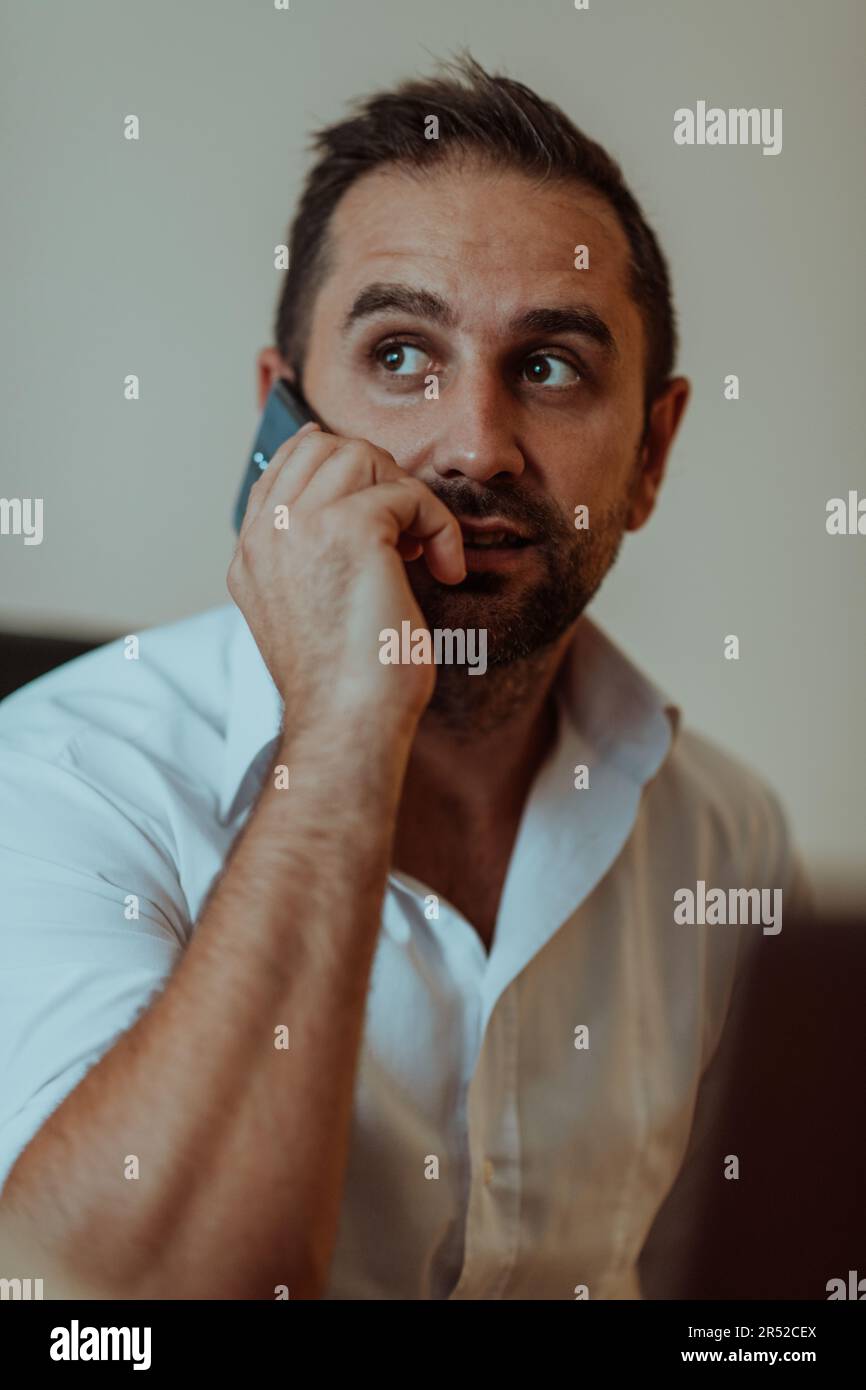 A businessman talking on his smartphone while seated in an office ...