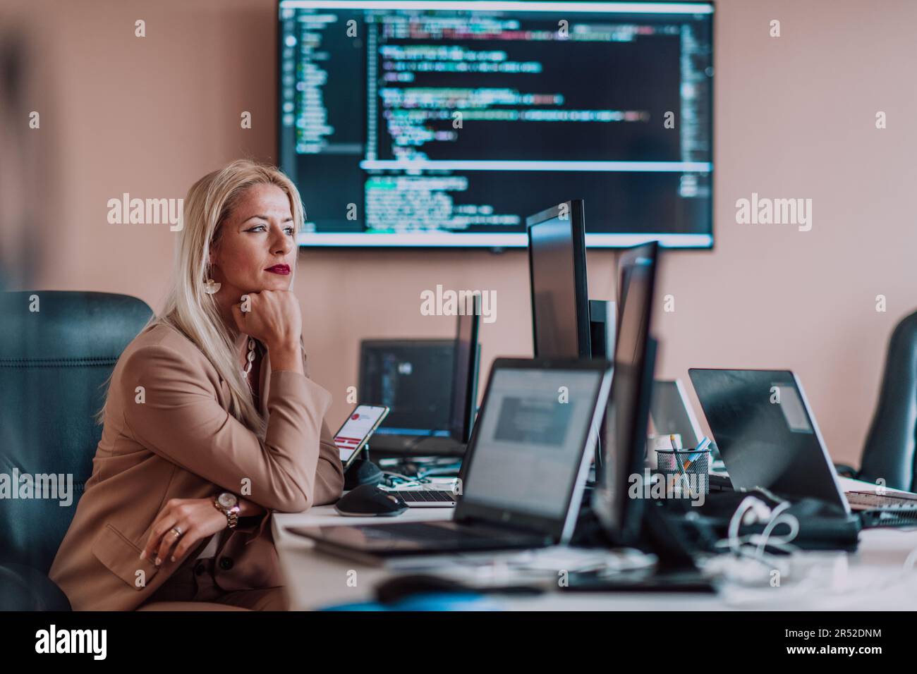 A businesswoman sitting in a programmer's office surrounded by ...