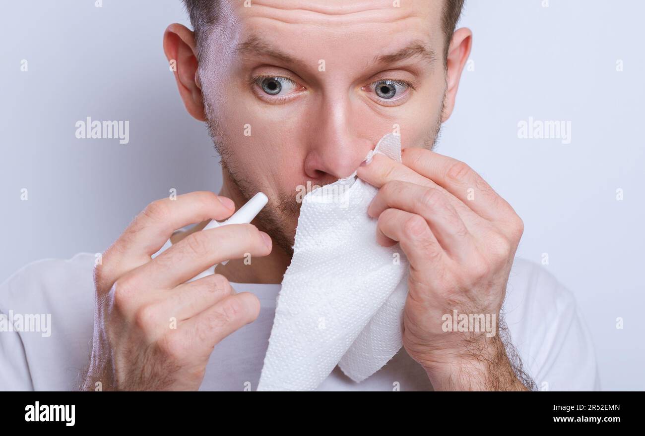 Guy dripping nasal drops in nose, portrait, close up Stock Photo
