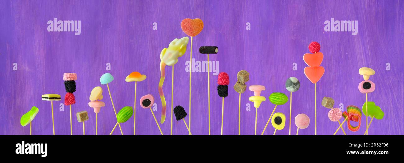 miscellaneous candy and sweets, close up, panoramic format, purple background Stock Photo