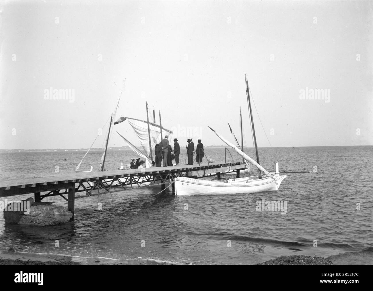 Group of men on a pontoon, next to a boat with 'Cannes' writed on it. Beginning of 20th century.This is an old photo digitized from glass plates. Stock Photo