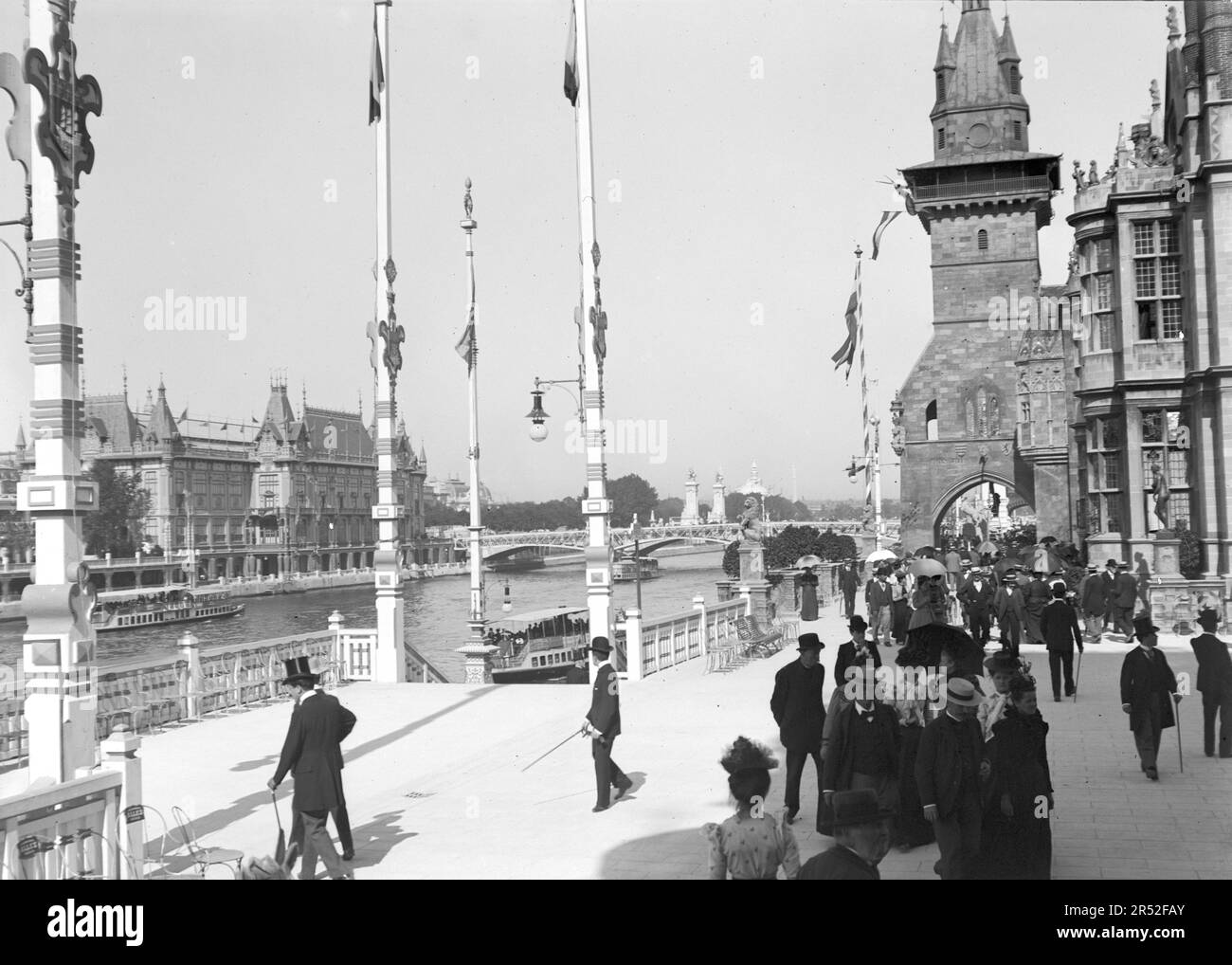 People walking in a paved street in Paris. With Alexandre III bridge in the background. Beginning of 20th century. Old photo digitized. Stock Photo