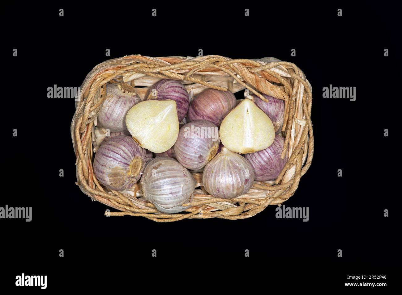 Tubers of alpine broad-leaf allium (Allium victorialis) in a woven basket, food photography with black background Stock Photo