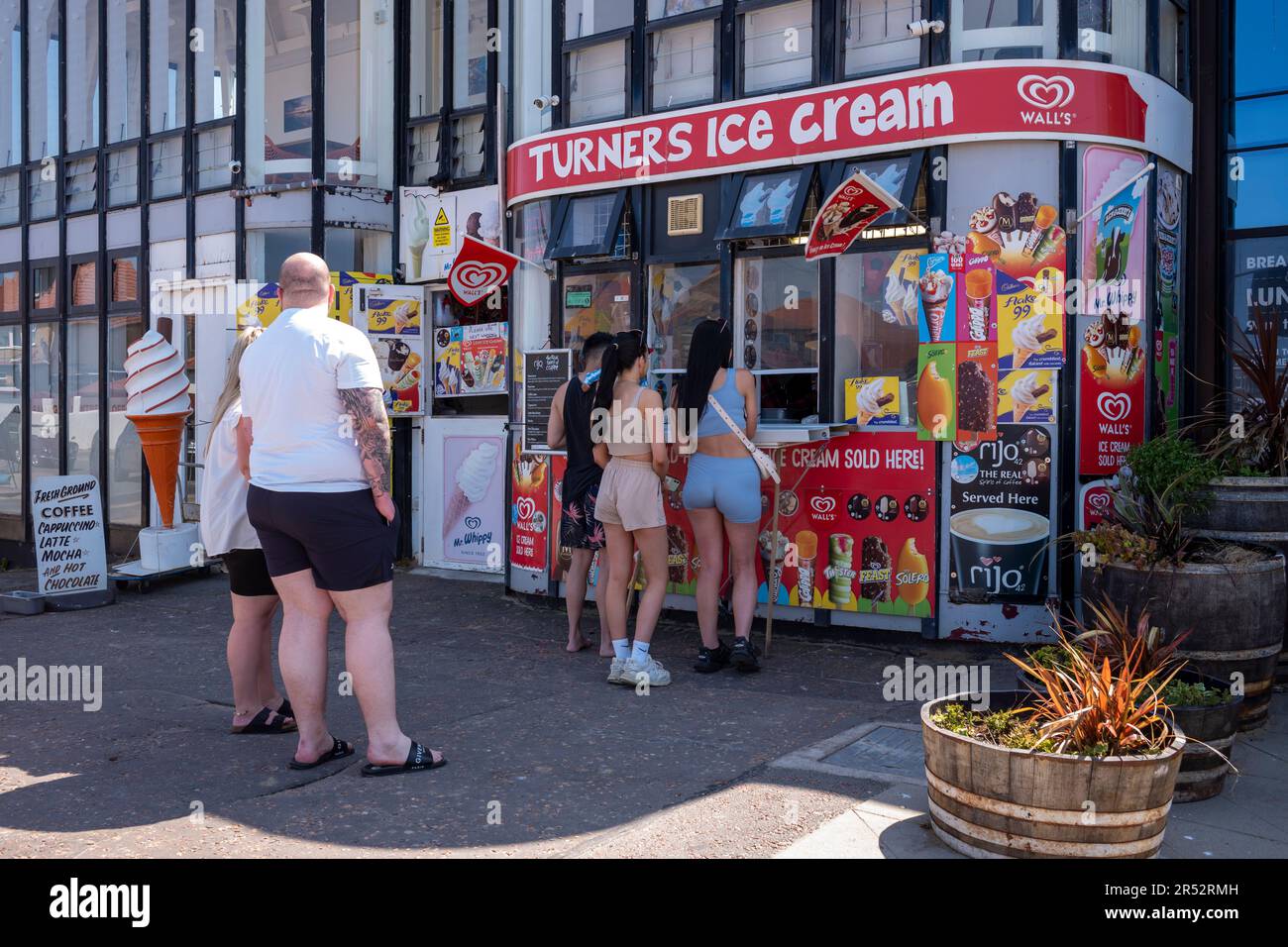 People buying and eating ice cream on West Kirby Beach Stock Photo