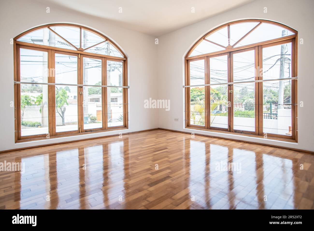 ventanales de habitacion en casa de campo iluminados, con acabados de parquet brillante y paredes color blanco Stock Photo