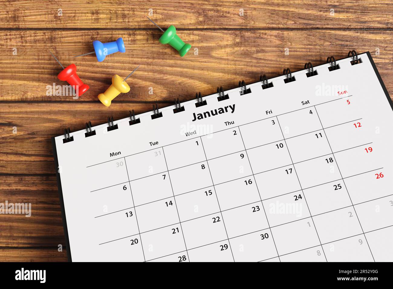 Colorful push pins scattered near a monthly desktop calendar on a