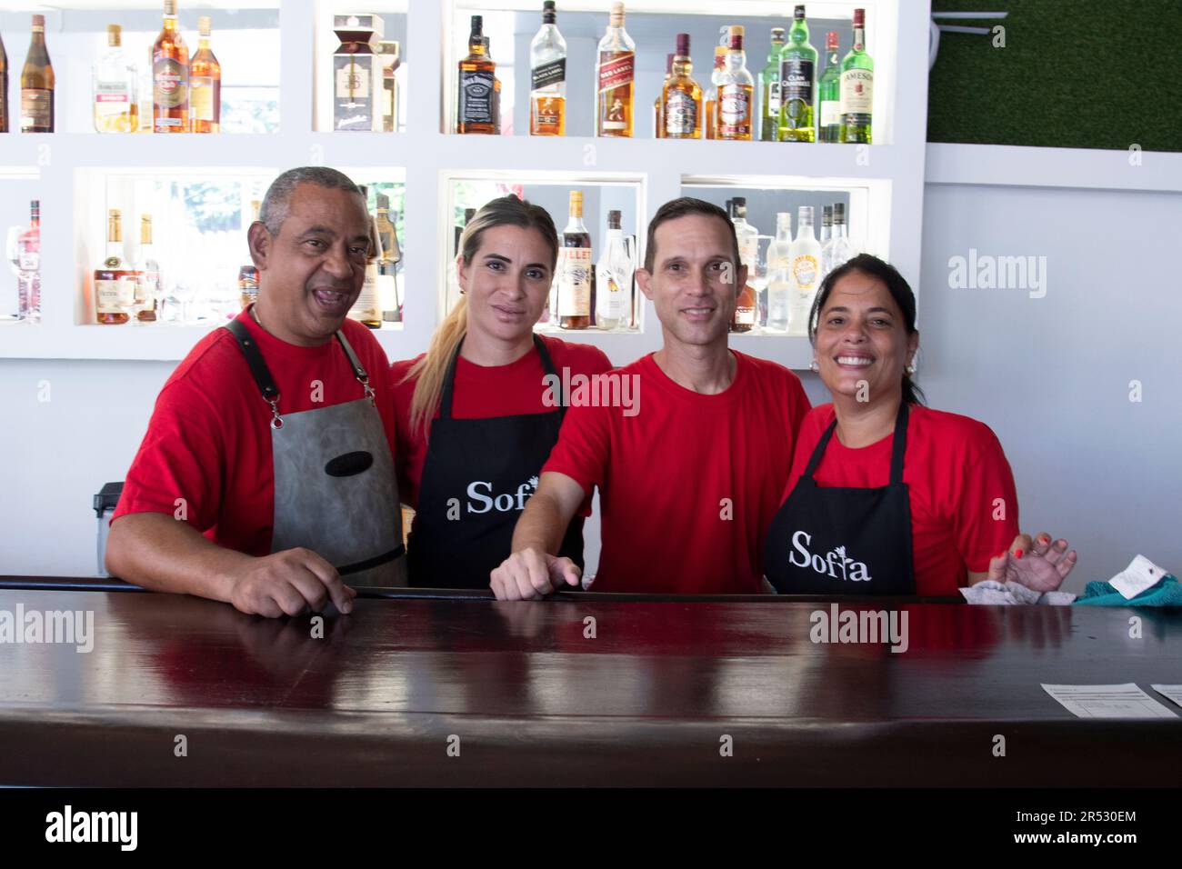 Cuban waiters smile at the camera in front of alcoholic beverages in La Habana Cuba. Stock Photo