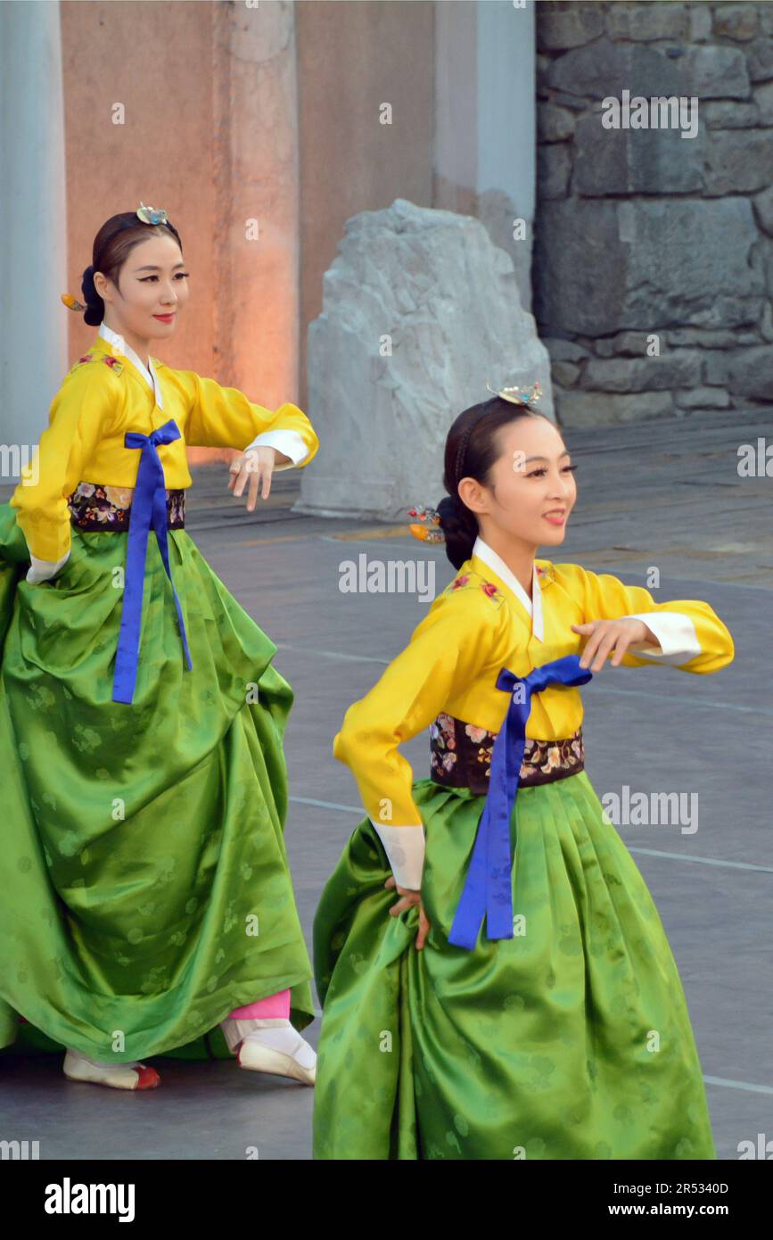 Beautiful women from the Republic of Korea in colorful costumes perform a traditional dance at the XXI International Folklore Festival in the ancient Stock Photo