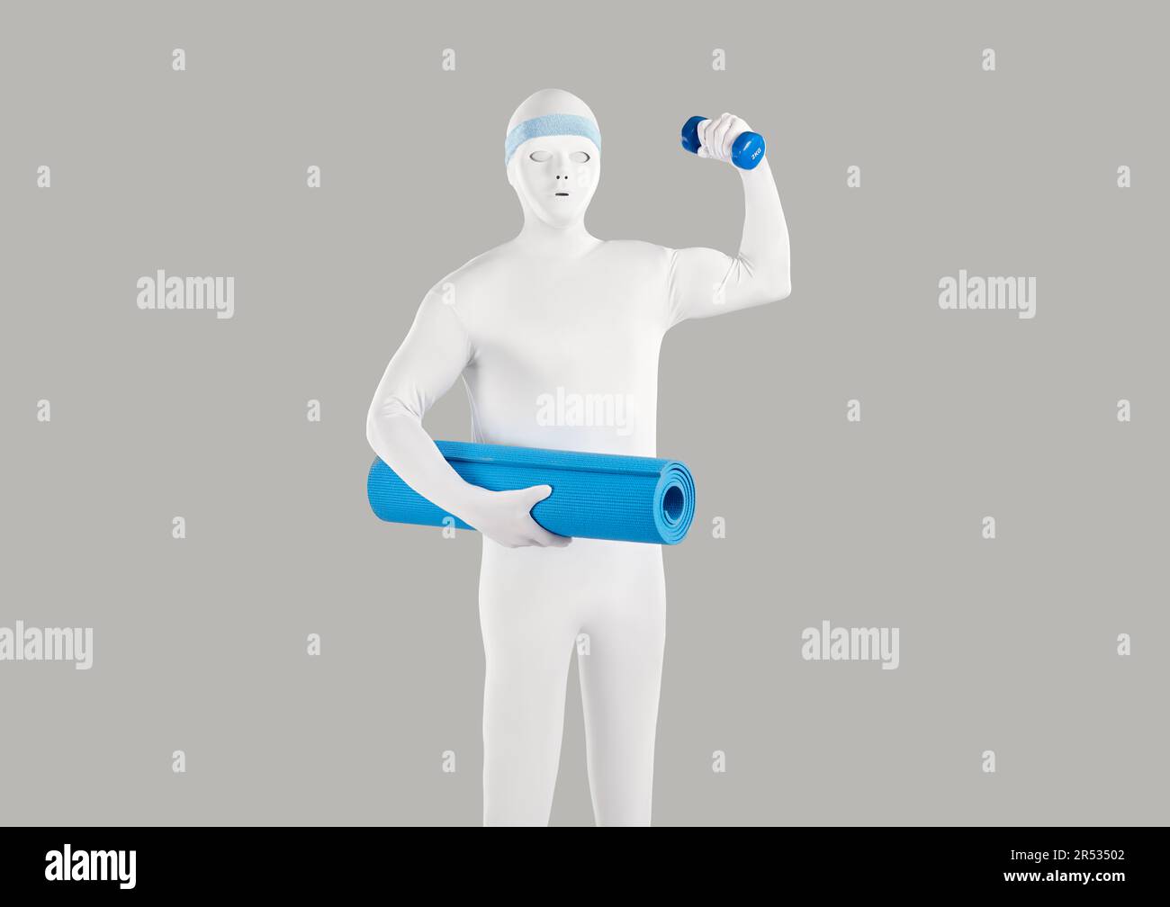 Fit man disguised in white bodysuit costume holding blue yoga mat and workout dumbbell Stock Photo