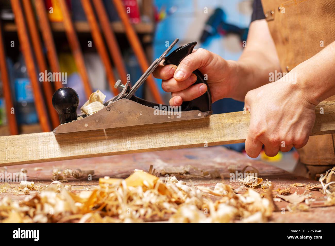 Carpenter's hands planing a plank of wood with a hand plane, workplace