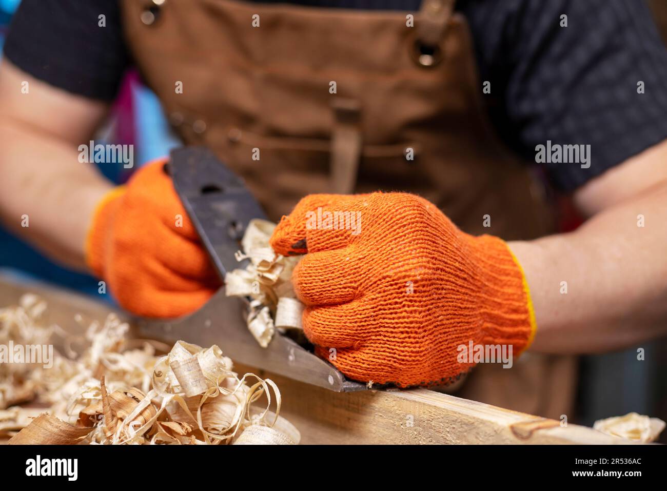 Carpenter's hands planing a plank of wood with a hand plane, workplace