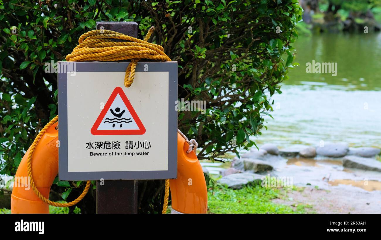 Beware of Deep Water warning sign at Yunhan Pond at the Chiang Kai-Shek Memorial Hall in Taipei, Taiwan; orange rope and lifesaver. Stock Photo