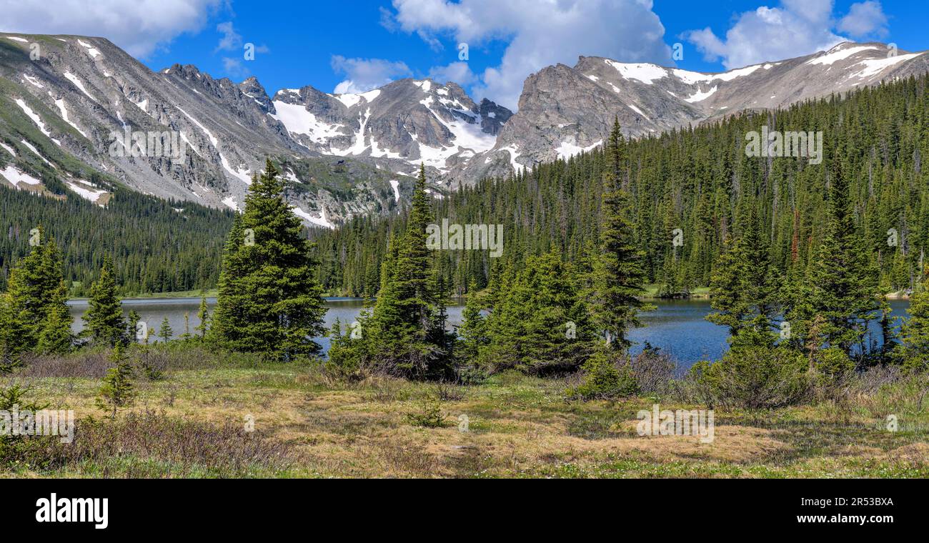 Indian Peaks at Long Lake - A panoramic view of rugged Indian Peaks at shore of Long Lake on a sunny Spring morning. Indian Peaks Wilderness, CO, USA. Stock Photo