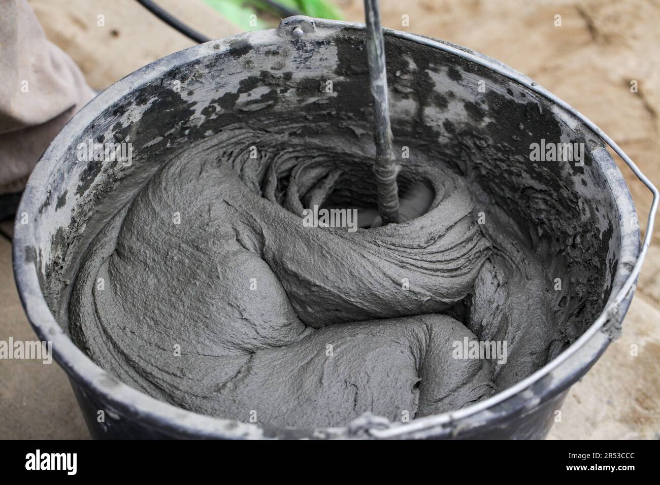 Cement based adhesive. Mixing concrete with an electric drill and mixer. Wet mortar for finishing works in construction. Stock Photo