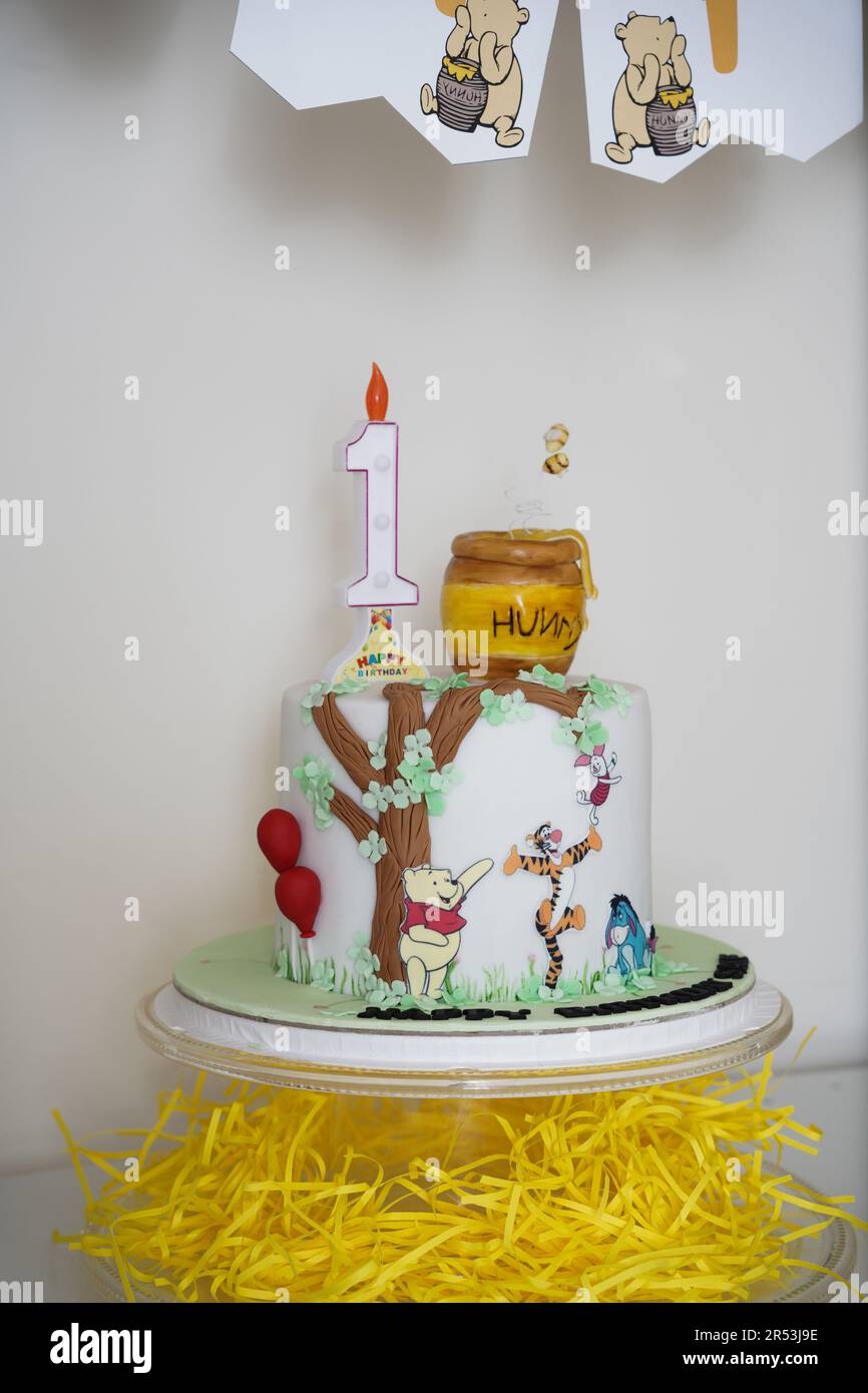 Winnie the Pooh birthday cake. Winnie the Pooh First year white birthday cake, a child birthday theme cake with sugar details and bunnies. Stock Photo