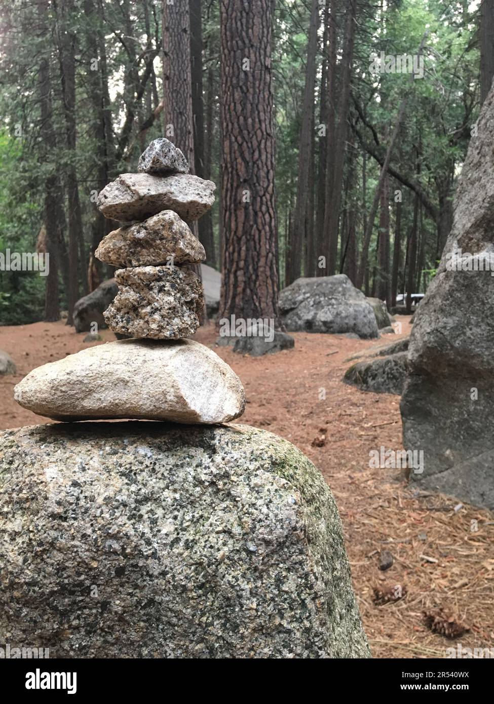 An upright pile of zen rocks creates a feeling of tranquility and inner peace in the forest of Yosemite National Park Stock Photo