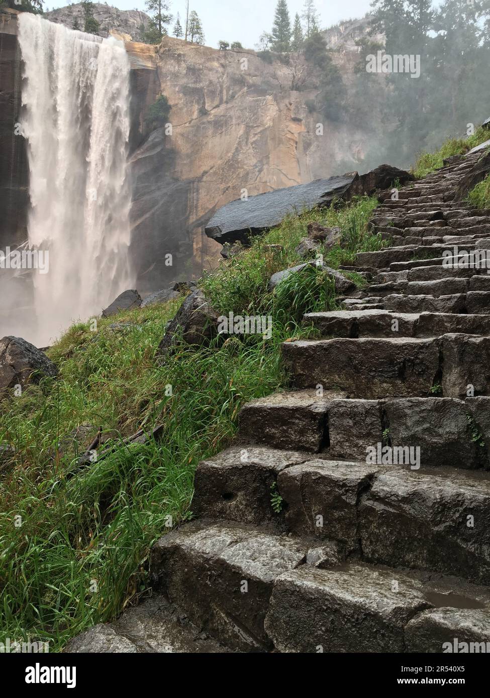 Steps are carved into side of a mountains as it climbs past the Vernal Falls waterfall in Yosemite National Park Stock Photo