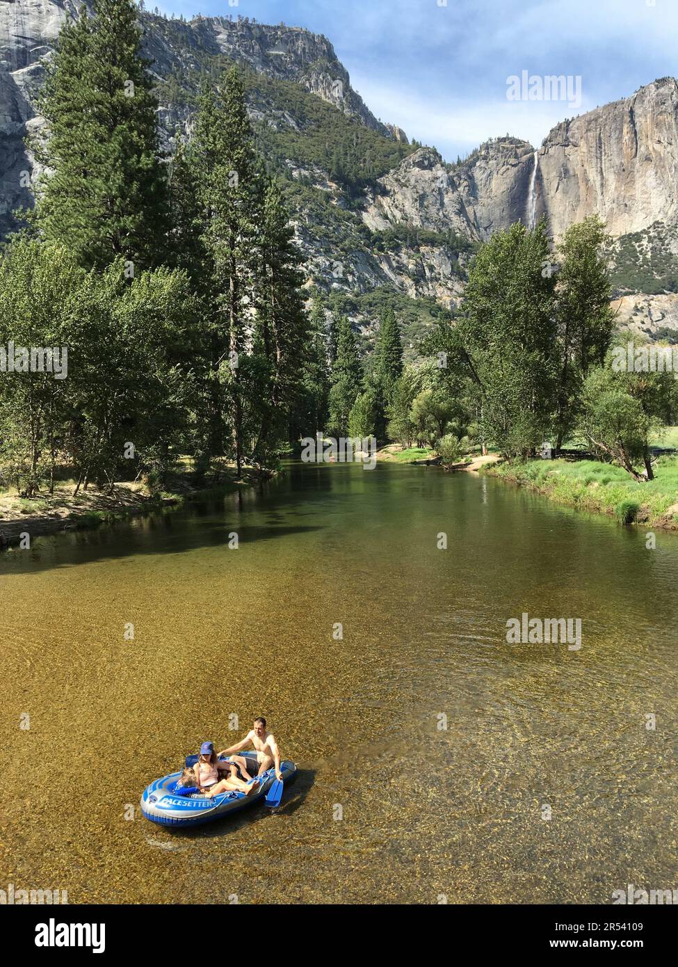 A family enjoys spending a summer vacation day together as their raft floats down the Merced River in Yosemite National Park Stock Photo