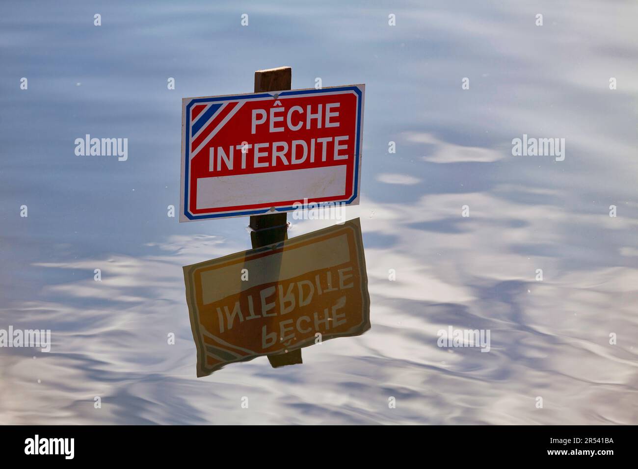 Sign popping out from the water saying in French 'Pêche interdite' meaning in English 'Fishing prohibited'. Stock Photo