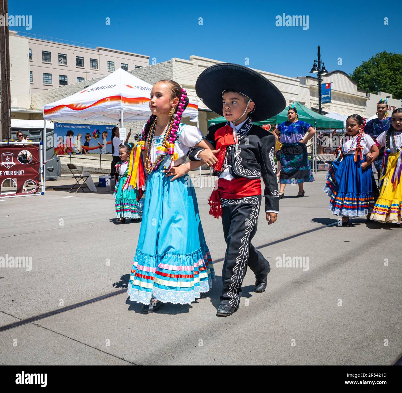 Two young people in traditional costumes walk together in a parade at the beginning of the Floricanto Family Festival, an event to honor Latin America Stock Photo