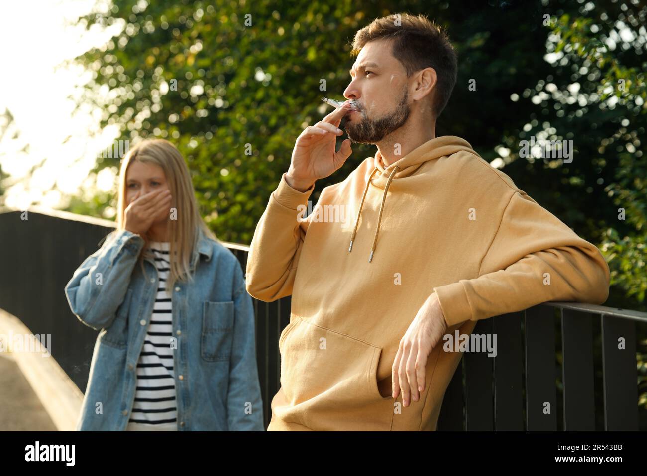 Handsome man smoking cigarette at public place outdoors Stock Photo