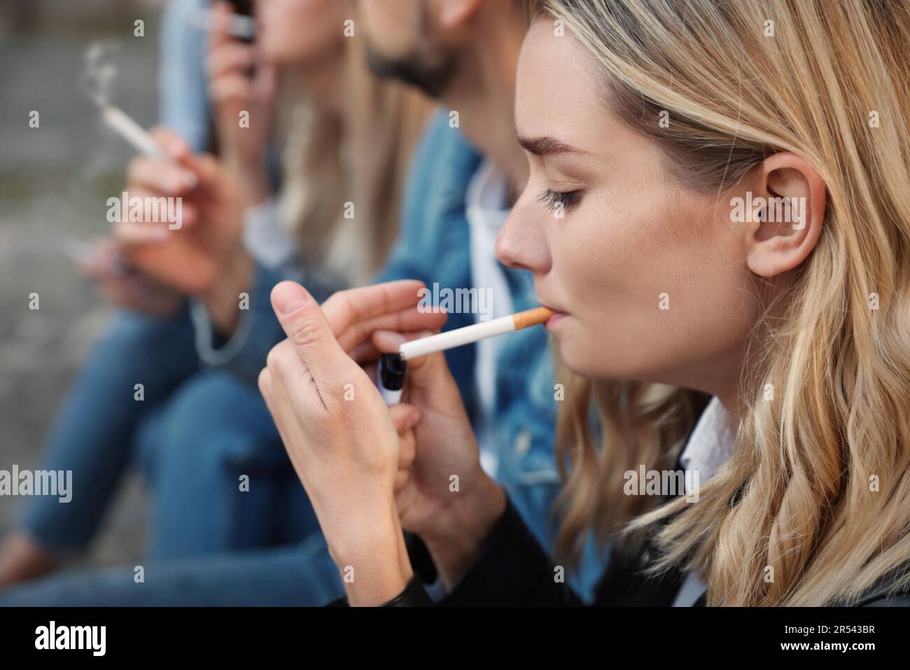 picture of someone smoking cigarettes People smoking cigarettes at public place outdoors, closeup Stock Photo