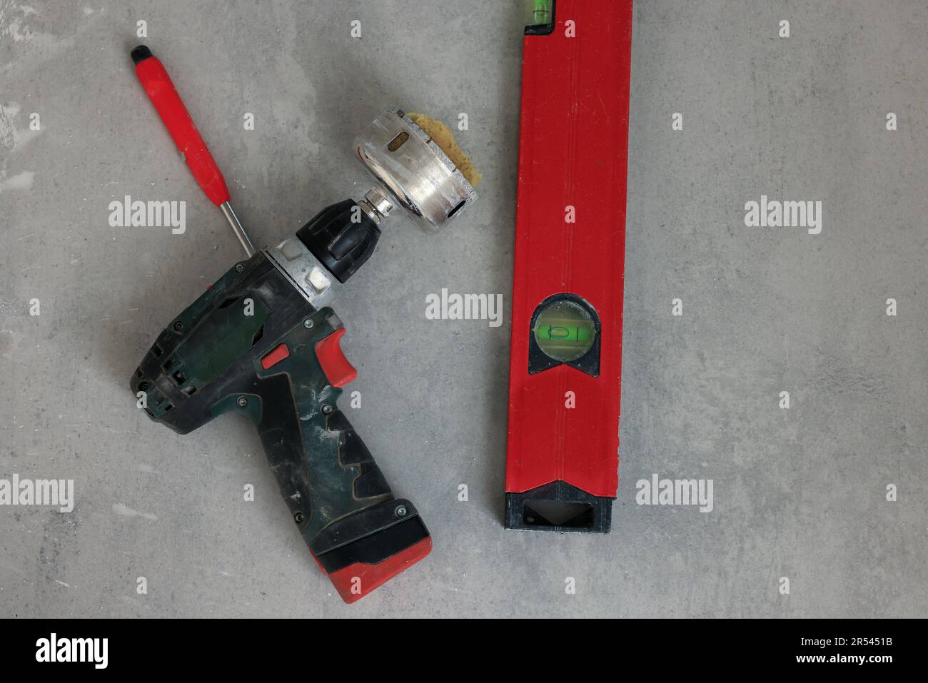 Buffing attachment drill and building level on floor, flat lay. Tiles