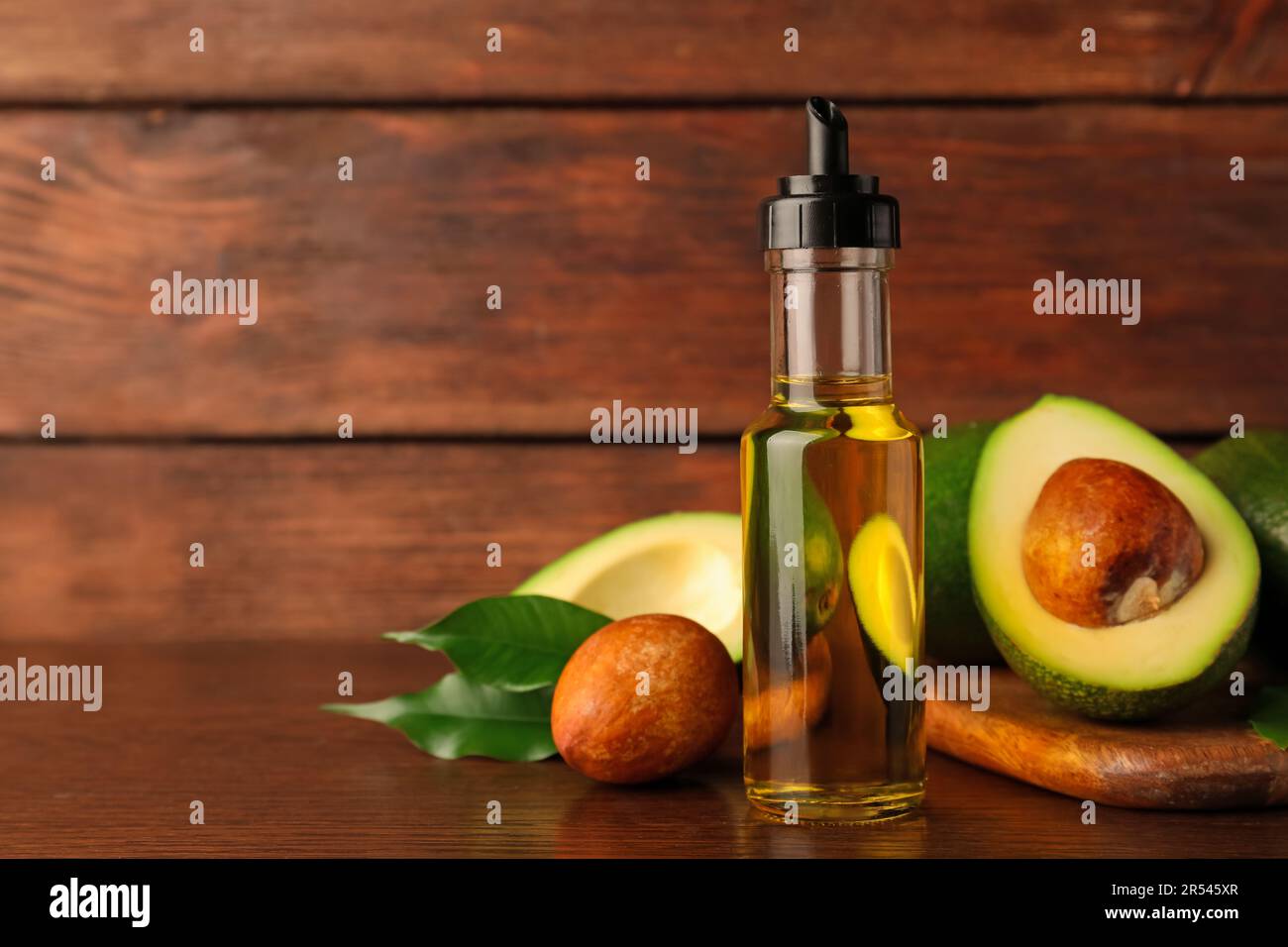 Glass bottle of cooking oil and fresh avocados on wooden table, space for text Stock Photo Alamy