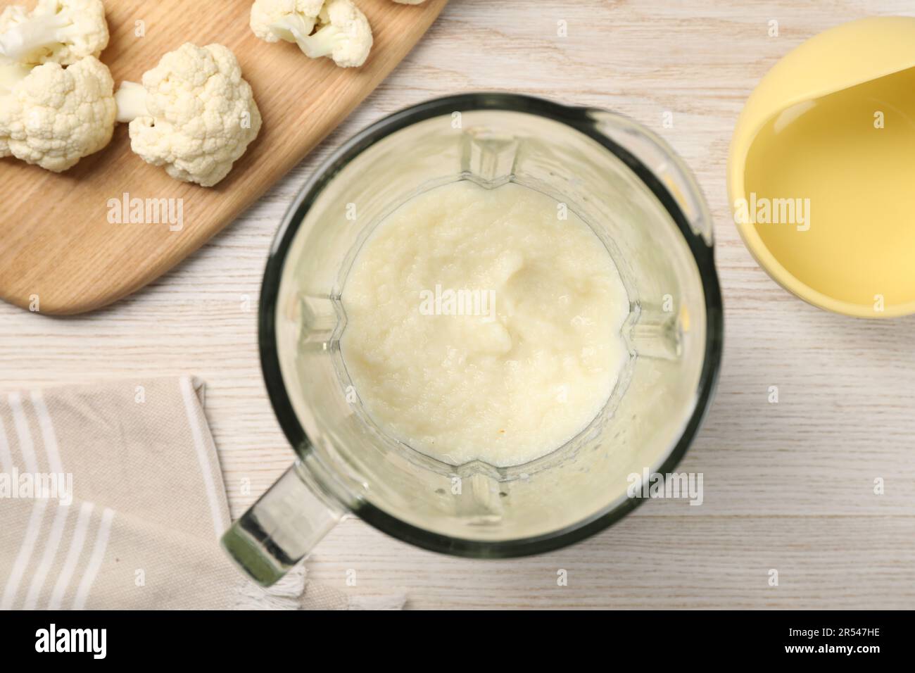Baby food. Blender with delicious cauliflower puree on light wooden table, flat lay Stock Photo