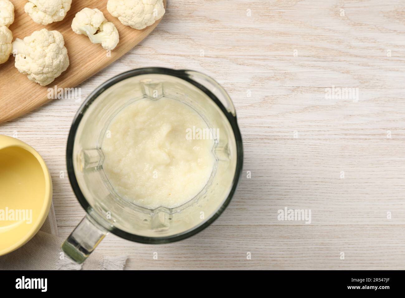 Baby food. Blender with delicious cauliflower puree on light wooden table, flat lay and space for text Stock Photo