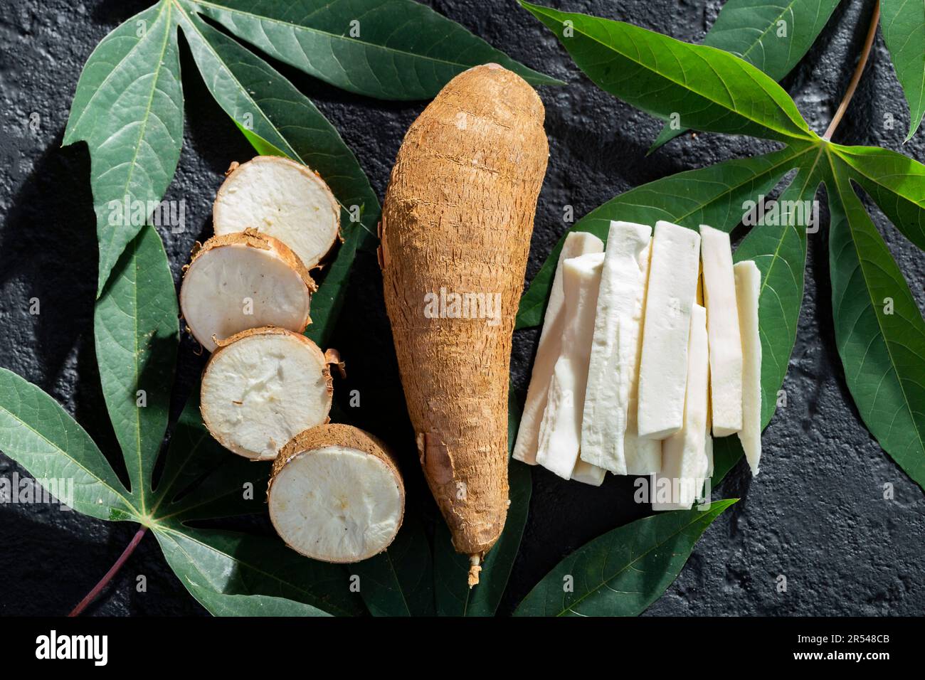 pile of cassava fruit and cassava flour on a background of rustic and dark texture (Manihot esculenta) Stock Photo