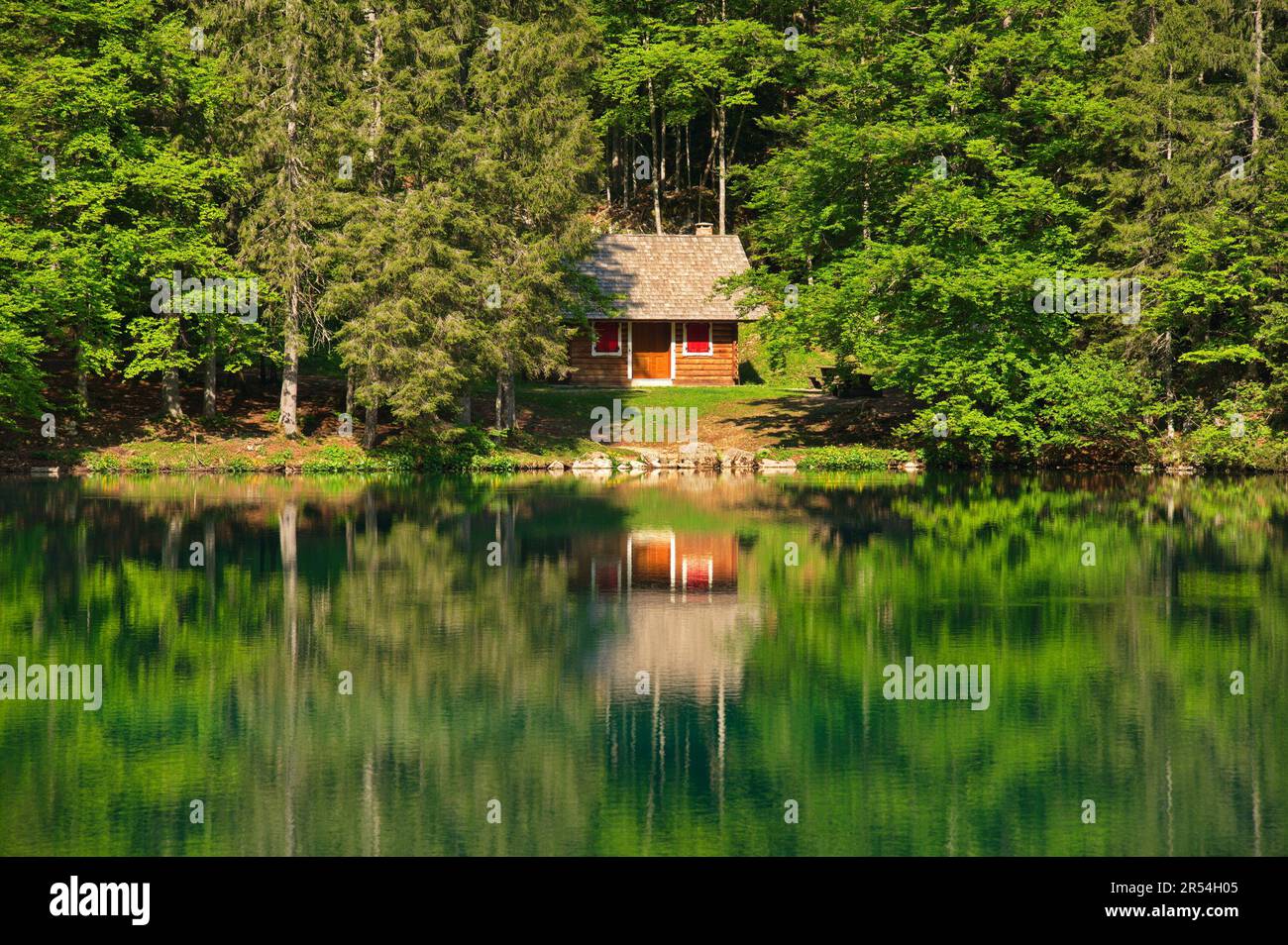 Wooden log cabin at the lake reflected in the water Stock Photo
