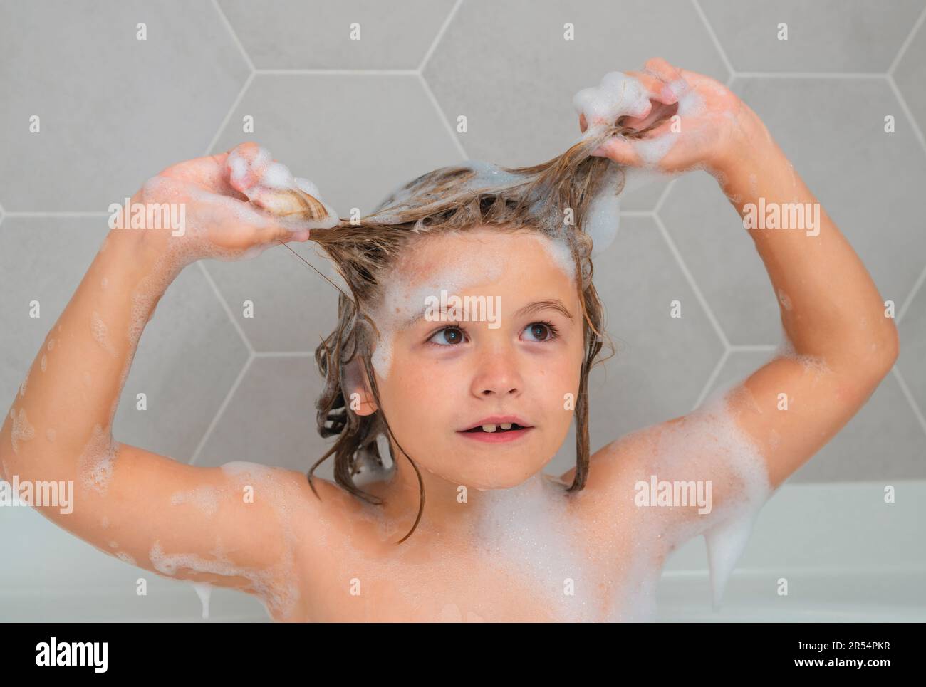 Kid washing hair. Soap on child head. Child face in foam. Kid bathing