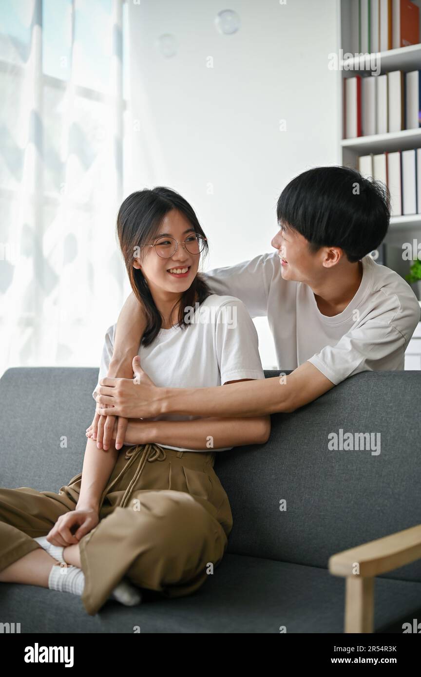 A cute and happy young Asian man embracing or hugging his girlfriend ...