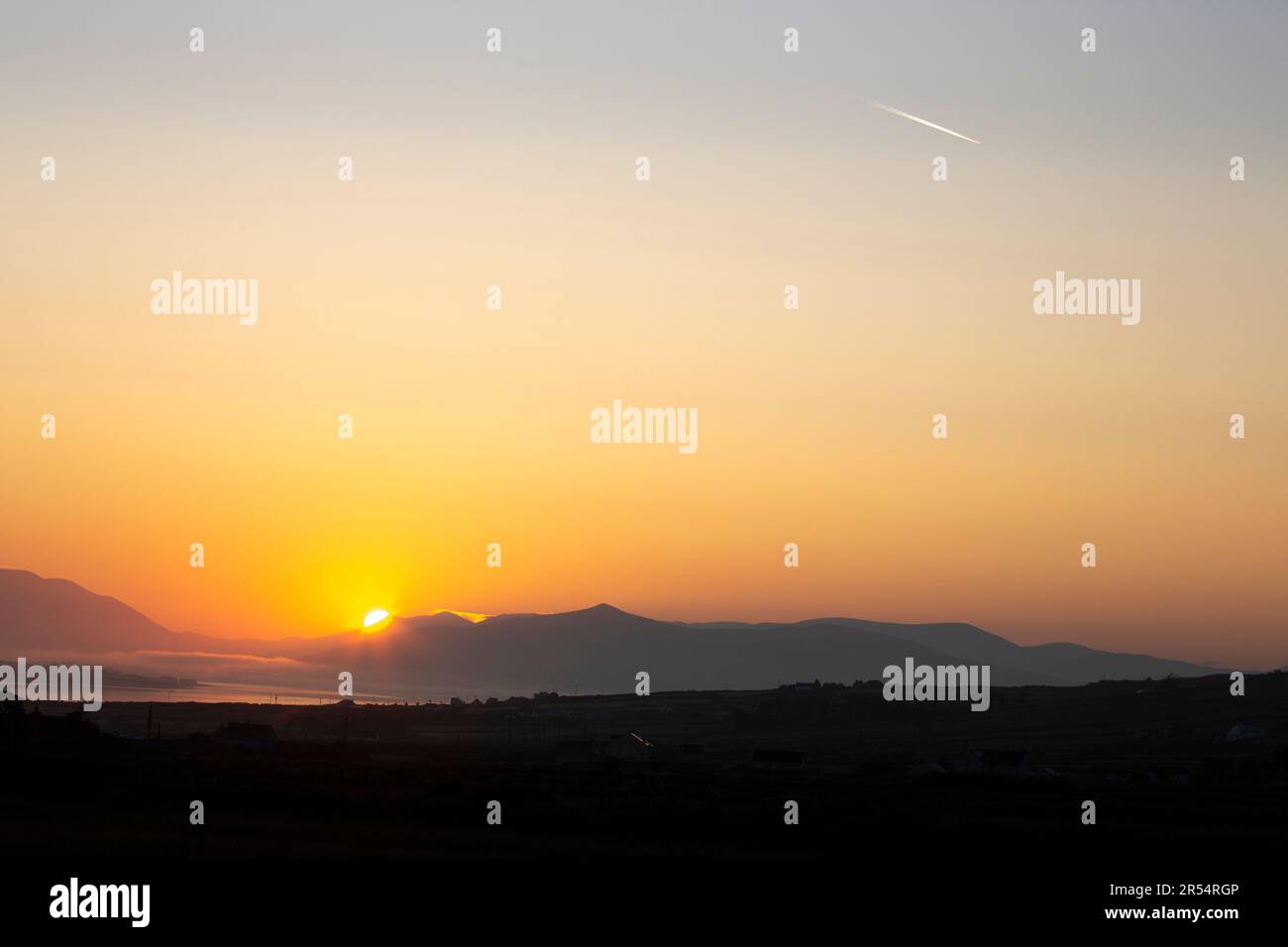 Portmagee, County Kerry, Ireland. 1st June 2023.  Glorious golden sunrise and jet trail over Portmagee Channel to herald in the first day of June. Photo Credit: Stephen Power / Alamy Live News Stock Photo