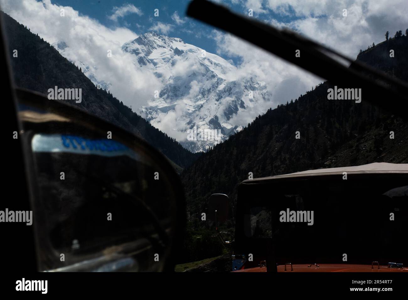 Journey to Serenity: Driving Towards Snow-Capped Mountains in Pakistan Stock Photo