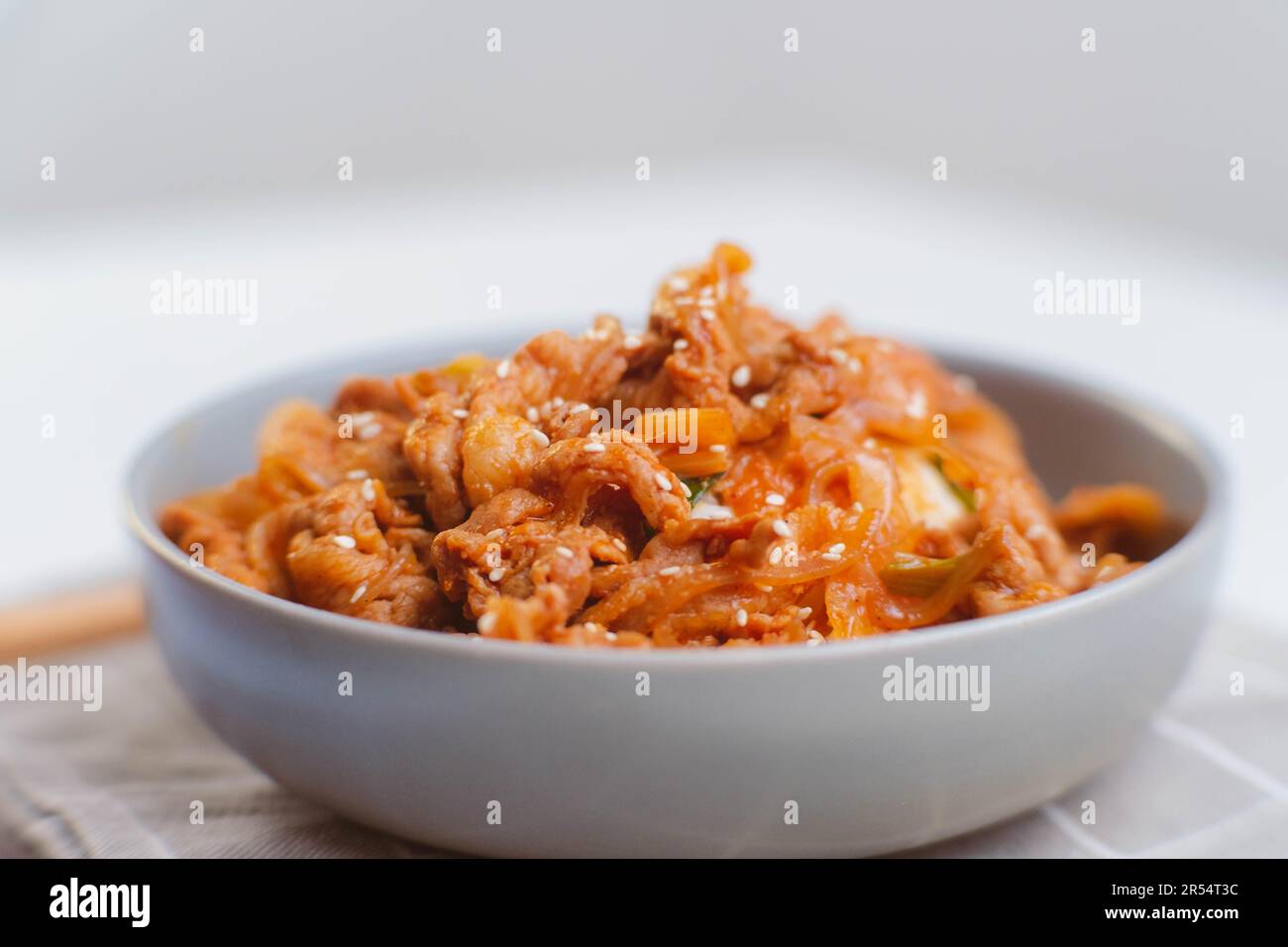 Stir fried kimchi and kurobuta pork on cooked rice in a bowl and serve ...