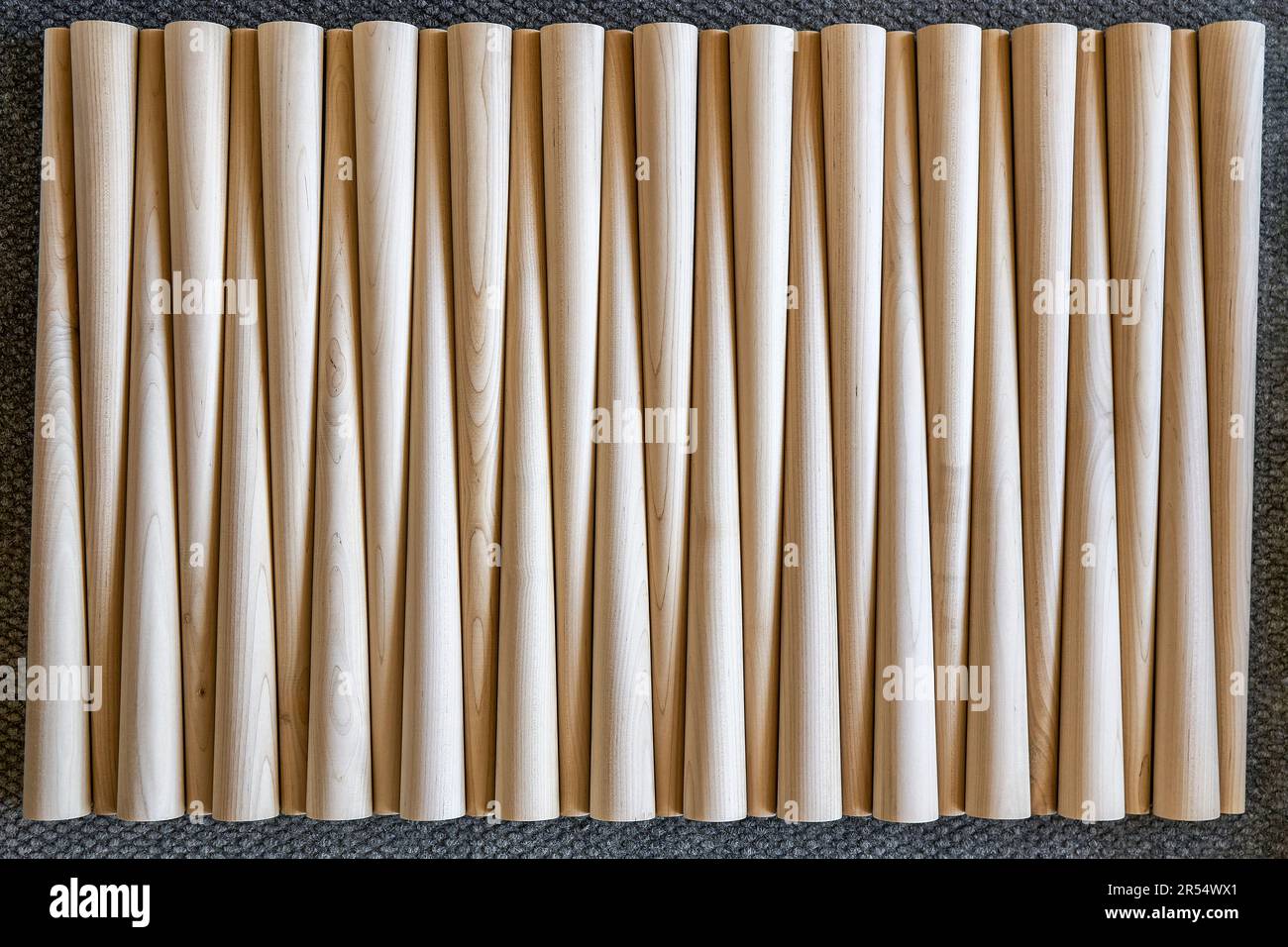 Pattern of polished conical wooden table legs on the gray carpet upper view. Prepared furniture details in furniture manufacturing workshop Stock Photo