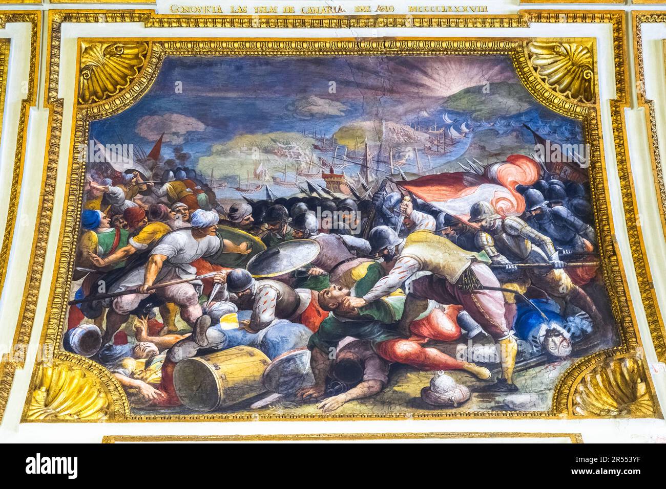 Painted ceiling framed by gilded stucco mouldings and inscriptions depicting the conquest of the Canary Island by Ferrante of Aragon - The ambassador's Hall in the Royal Palace of Naples that In 1734 became the royal residence of the Bourbons - Naples, Italy Stock Photo