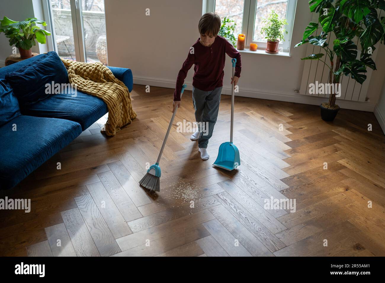 Child boy sweeps floor do house chores, domestic cleanup. Habit of