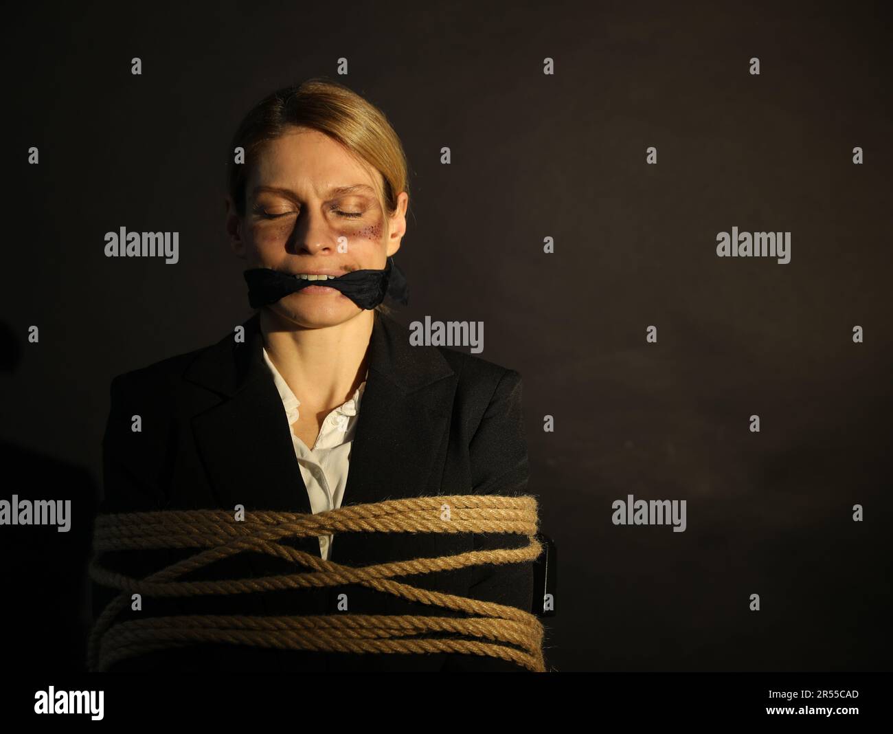 Woman with bruises tied up and taken hostage on dark background. Space for text Stock Photo Alamy