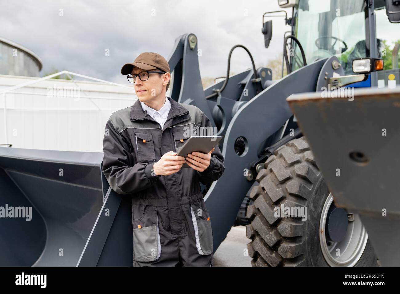 Serviceman with digital tablet on a background of the tractor. High quality photo Stock Photo