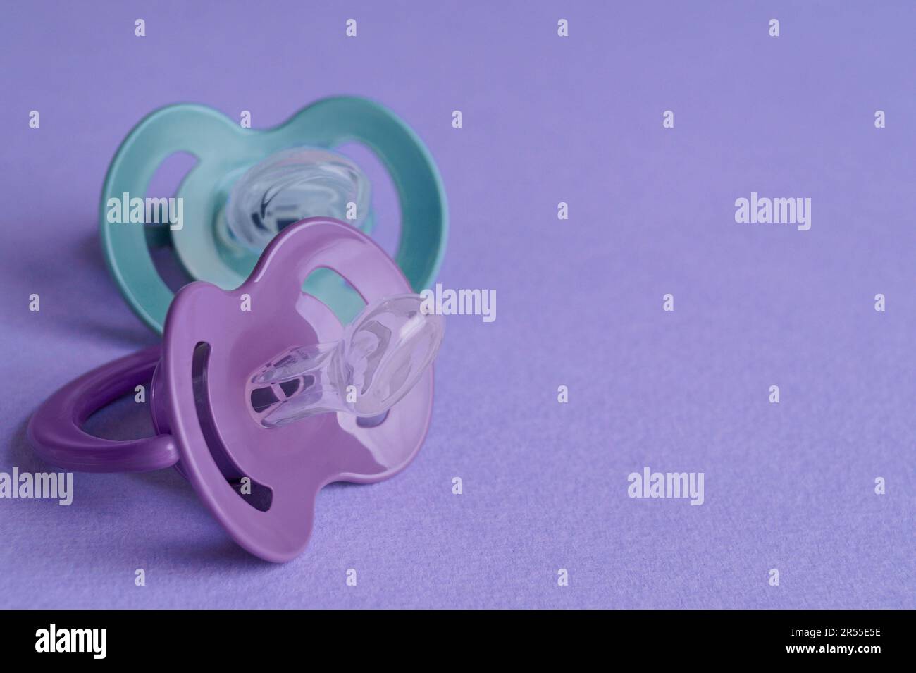 New baby pacifiers on purple background, closeup. Space for text Stock ...